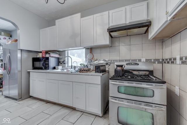 952 Lasalle St, Indianapolis, IN 46201 - kitchen with appliances with stainless steel finishes, under cabinet range hood, arched walkways, white cabinets, and a sink