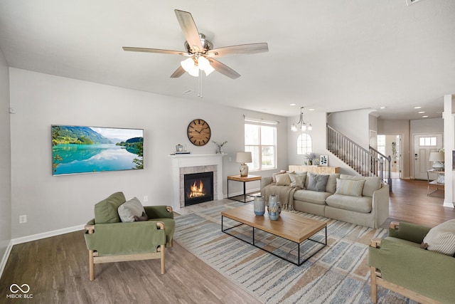 6830 Park Grove Blvd, Whitestown, IN 46075 - living area with wood finished floors, baseboards, a tiled fireplace, a ceiling fan, and stairs