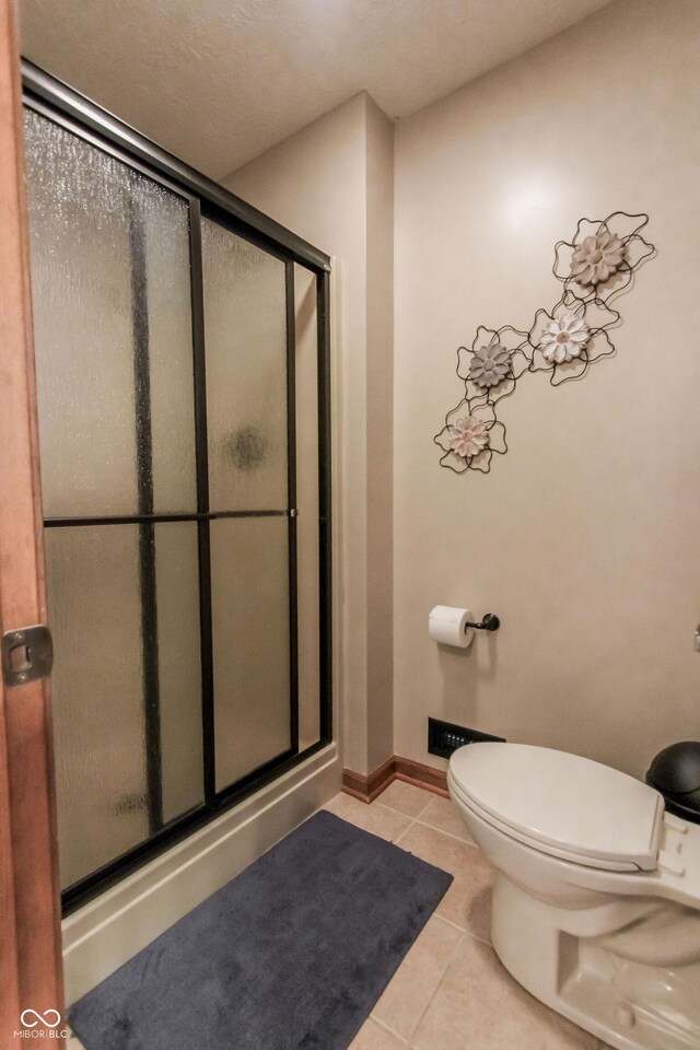 3819 S Village Dr, New Palestine, IN 46163 - bathroom featuring a stall shower, tile patterned floors, toilet, and baseboards