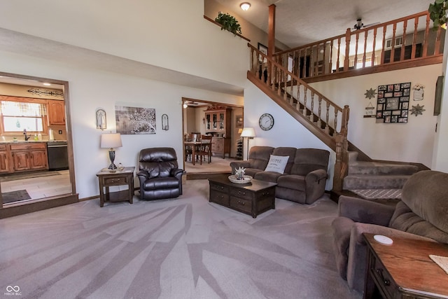 3819 S Village Dr, New Palestine, IN 46163 - living area featuring light carpet, stairs, a high ceiling, and baseboards