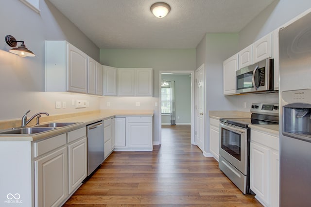 2234 Burgundy Way, Plainfield, IN 46168 - kitchen with stainless steel appliances, a sink, a textured ceiling, light wood finished floors, and white cabinets