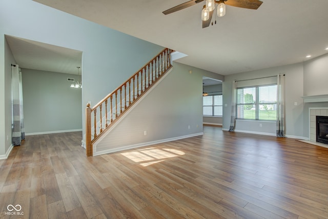 2234 Burgundy Way, Plainfield, IN 46168 - unfurnished living room with stairway, a tiled fireplace, ceiling fan, wood finished floors, and baseboards