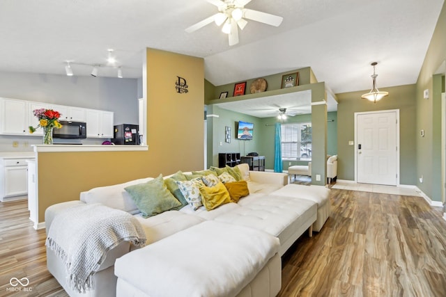2114 Turning Leaf Dr, Franklin, IN 46131 - living area featuring ceiling fan, vaulted ceiling, light wood-style flooring, and baseboards
