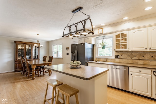 7935 N County Road 650 E, Brownsburg, IN 46112 - kitchen with stainless steel dishwasher, black fridge with ice dispenser, a kitchen bar, light wood-type flooring, and a textured ceiling