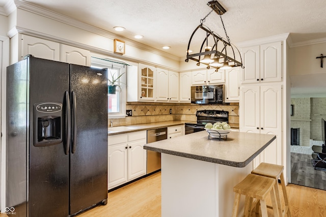 7935 N County Road 650 E, Brownsburg, IN 46112 - kitchen featuring black appliances, a kitchen breakfast bar, light wood finished floors, crown molding, and white cabinets