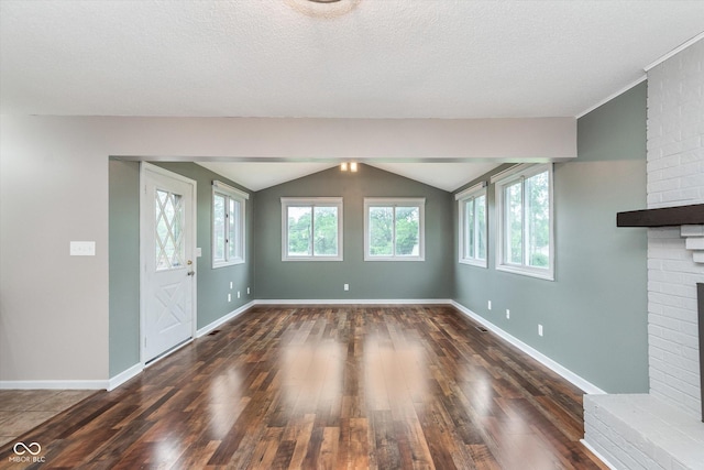8205 Picadilly Ln, Indianapolis, IN 46256 - unfurnished living room featuring a brick fireplace, wood finished floors, vaulted ceiling, baseboards, and a textured ceiling