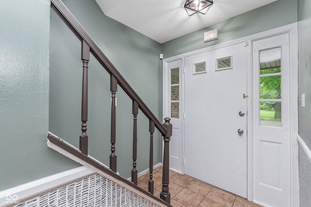 8205 Picadilly Ln, Indianapolis, IN 46256 - foyer entrance featuring light tile patterned floors, stairway, a textured ceiling, and baseboards