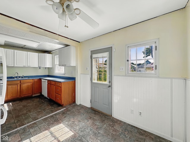621 N Livingston Ave, Indianapolis, IN 46222 - kitchen with dishwasher, a ceiling fan, a wainscoted wall, dark stone finish floors, and white cabinets