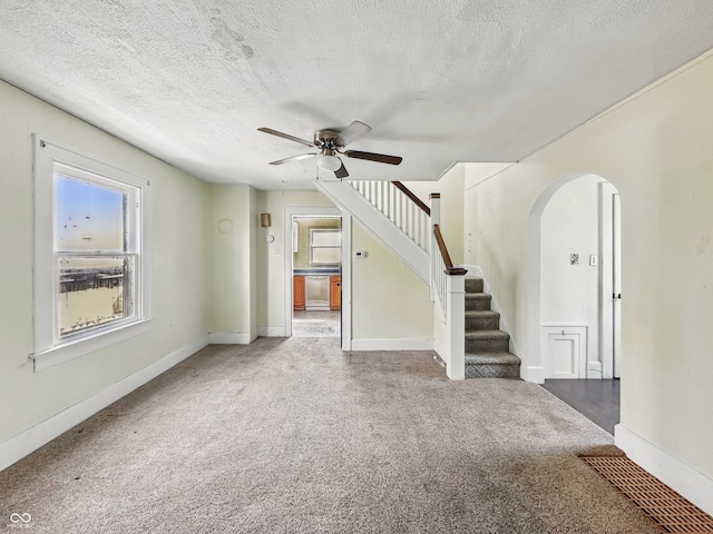 621 N Livingston Ave, Indianapolis, IN 46222 - unfurnished living room featuring arched walkways, a ceiling fan, carpet flooring, healthy amount of natural light, and a textured ceiling