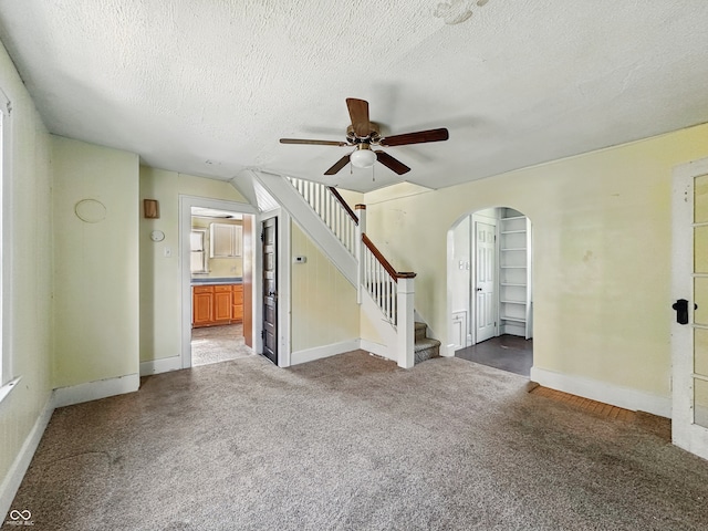 621 N Livingston Ave, Indianapolis, IN 46222 - unfurnished living room featuring carpet flooring, ceiling fan, arched walkways, stairway, and baseboards