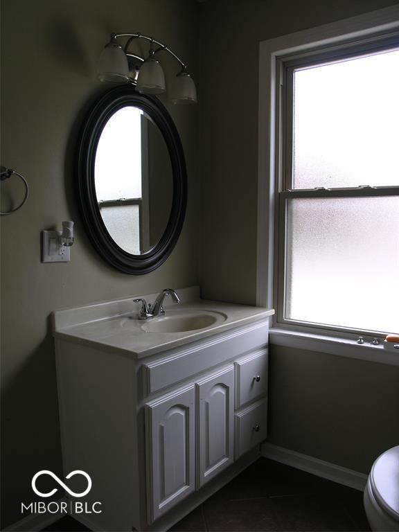 3456 S Sadlier Dr S, Indianapolis, IN 46239 - bathroom with vanity, toilet, tile patterned flooring, and baseboards