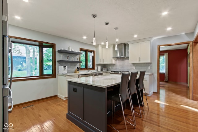 7426 Shadow Wood Dr, Indianapolis, IN 46254 - kitchen with wall chimney exhaust hood, white cabinetry, light wood finished floors, backsplash, and recessed lighting