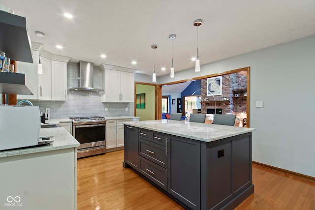7426 Shadow Wood Dr, Indianapolis, IN 46254 - kitchen with wall chimney range hood, gas stove, white cabinetry, light wood-style floors, and recessed lighting