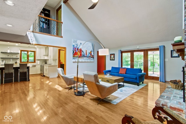 7426 Shadow Wood Dr, Indianapolis, IN 46254 - living room with light wood-type flooring, high vaulted ceiling, a ceiling fan, baseboards, and a textured ceiling