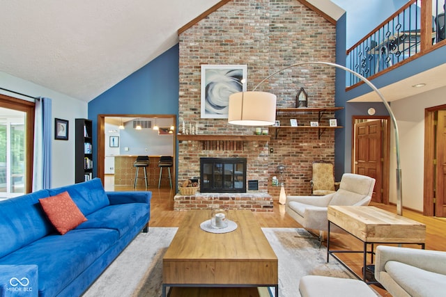 7426 Shadow Wood Dr, Indianapolis, IN 46254 - living area featuring high vaulted ceiling, wood finished floors, a brick fireplace, and a textured ceiling