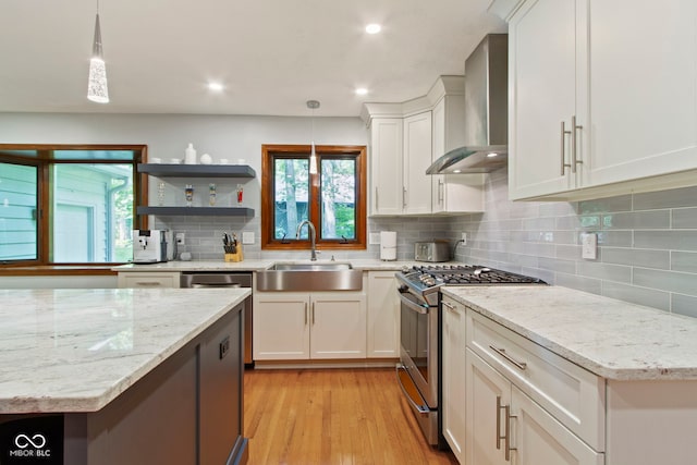 7426 Shadow Wood Dr, Indianapolis, IN 46254 - kitchen featuring stainless steel range with gas stovetop, wall chimney range hood, a sink, white cabinets, and backsplash