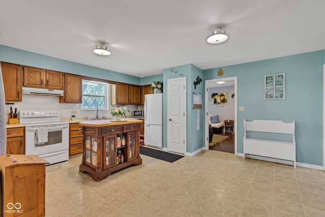 12121 E 21st St, Indianapolis, IN 46229 - kitchen featuring white appliances, light countertops, a sink, brown cabinetry, and under cabinet range hood