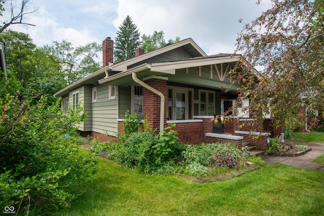 5133 E Michigan St, Indianapolis, IN 46219 - view of home's exterior with a chimney, a yard, a porch, and brick siding