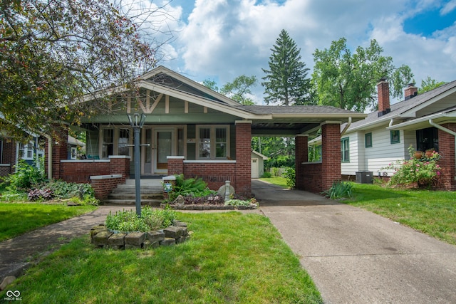 5133 E Michigan St, Indianapolis, IN 46219 - view of front of home with covered porch, brick siding, concrete driveway, a front yard, and an attached carport
