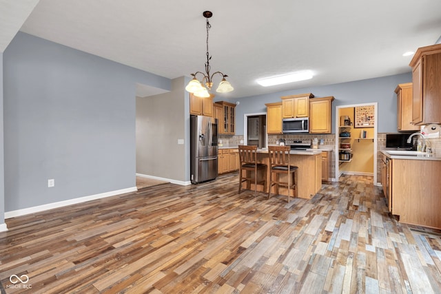 13766 Heatherfield Dr, Fishers, IN 46038 - kitchen with stainless steel appliances, a kitchen island, light wood finished floors, and backsplash