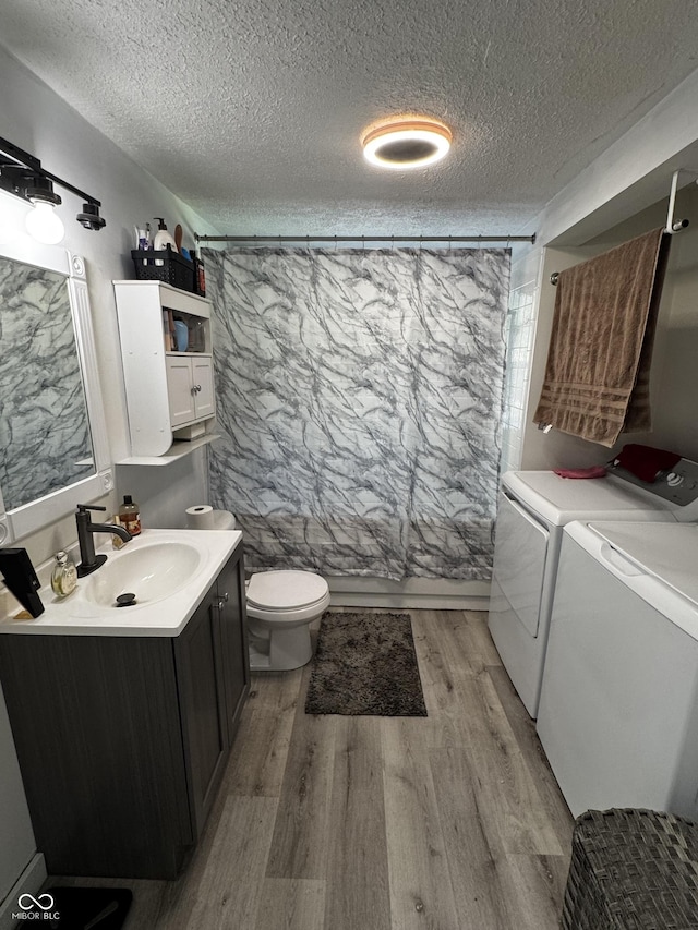 1206 Mcdougal St, Indianapolis, IN 46203 - bathroom with washer and dryer, vanity, wood finished floors, a textured ceiling, and toilet