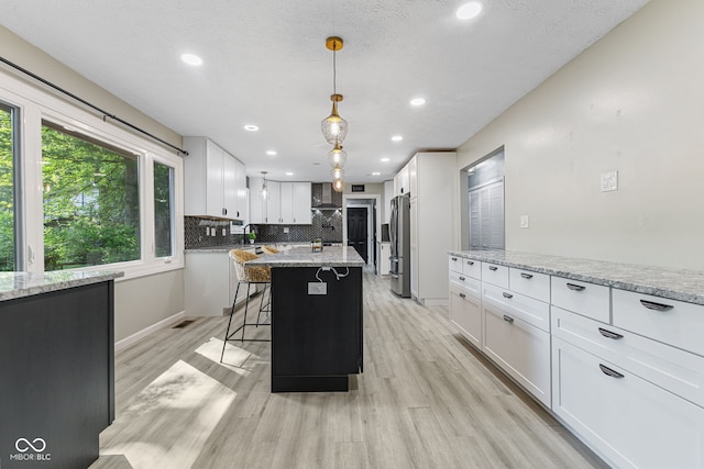 7630 Blain Way, Indianapolis, IN 46254 - kitchen featuring freestanding refrigerator, wall chimney range hood, light wood finished floors, tasteful backsplash, and white cabinets