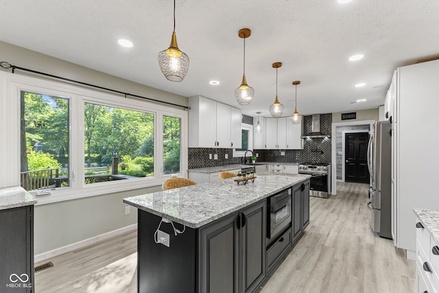 7630 Blain Way, Indianapolis, IN 46254 - kitchen featuring wall chimney exhaust hood, appliances with stainless steel finishes, dark cabinets, white cabinets, and light wood-type flooring