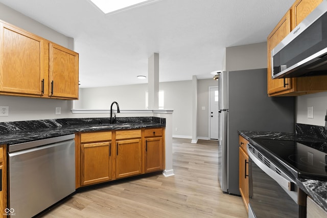 1313 Kenwood Dr, Greenwood, IN 46143 - kitchen featuring stainless steel appliances, a sink, light wood-type flooring, dark stone countertops, and a peninsula