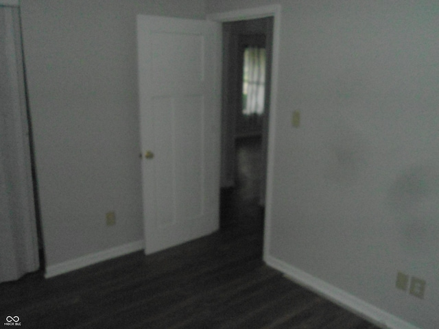 spare room featuring baseboards and dark wood-style flooring