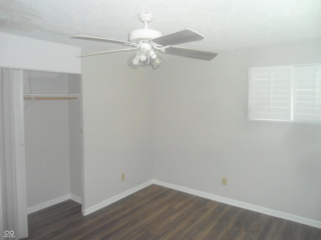 unfurnished bedroom with dark wood-type flooring, a closet, baseboards, and a ceiling fan
