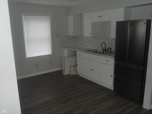 kitchen featuring freestanding refrigerator, a sink, white cabinetry, dark wood finished floors, and backsplash