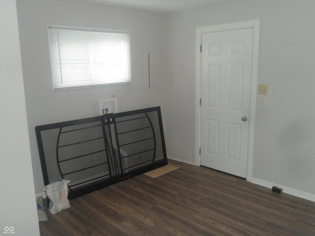 empty room with wood finished floors, baseboards, and electric panel