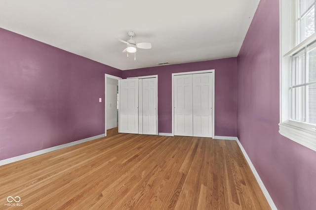 308 Hickory Hill Dr, Terre Haute, IN 47802 - unfurnished bedroom featuring multiple closets, baseboards, light wood-style flooring, and a ceiling fan