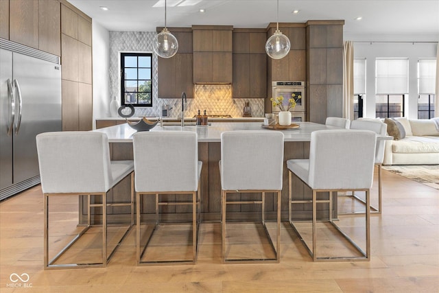 1818 N Pennsylvania St, Indianapolis, IN 46202 - kitchen with appliances with stainless steel finishes, modern cabinets, light countertops, a kitchen breakfast bar, and tasteful backsplash