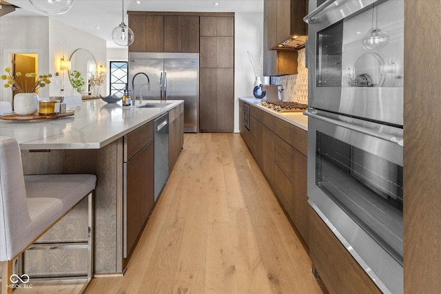 1818 N Pennsylvania St, Indianapolis, IN 46202 - kitchen featuring modern cabinets, stainless steel appliances, light wood-type flooring, decorative light fixtures, and backsplash