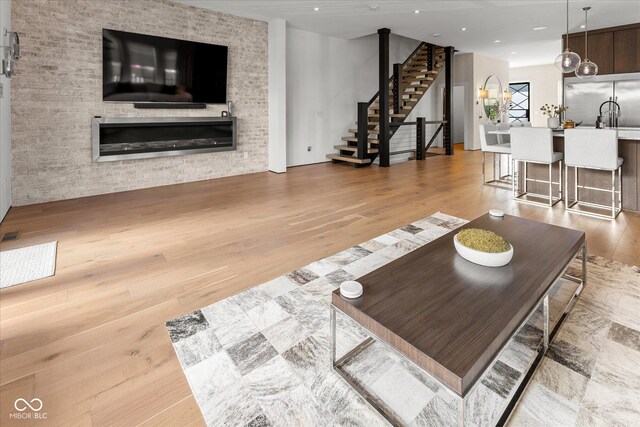 1818 N Pennsylvania St, Indianapolis, IN 46202 - living room featuring stairs, light wood-type flooring, a glass covered fireplace, and recessed lighting