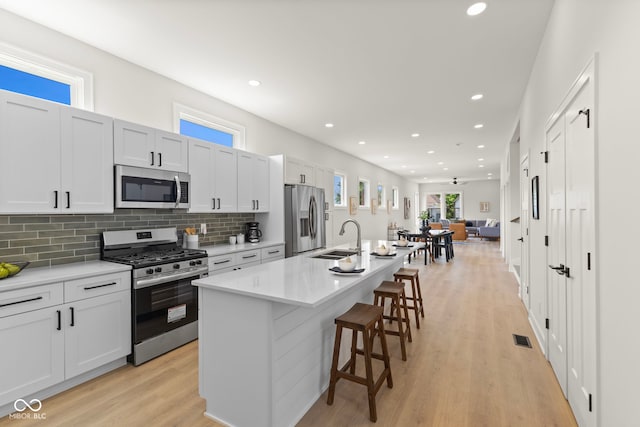 1405 Deloss St, Indianapolis, IN 46201 - kitchen with appliances with stainless steel finishes, a sink, a center island with sink, a breakfast bar area, and decorative backsplash