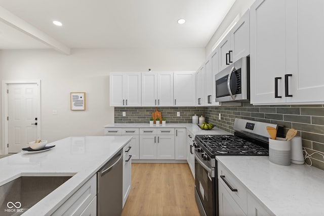 1405 Deloss St, Indianapolis, IN 46201 - kitchen with stainless steel appliances, tasteful backsplash, light stone counters, light wood-style floors, and recessed lighting