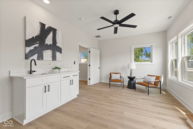 1405 Deloss St, Indianapolis, IN 46201 - sitting room featuring wet bar, light wood-type flooring, a ceiling fan, and baseboards