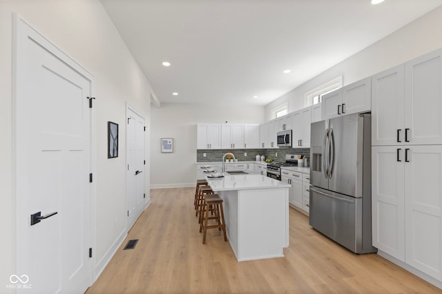 1405 Deloss St, Indianapolis, IN 46201 - kitchen featuring appliances with stainless steel finishes, a sink, a breakfast bar, backsplash, and recessed lighting
