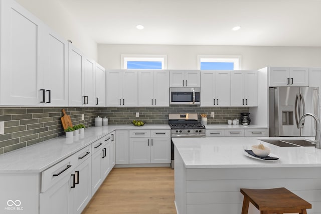 1405 Deloss St, Indianapolis, IN 46201 - kitchen featuring stainless steel appliances, a sink, backsplash, a breakfast bar, and light stone counters
