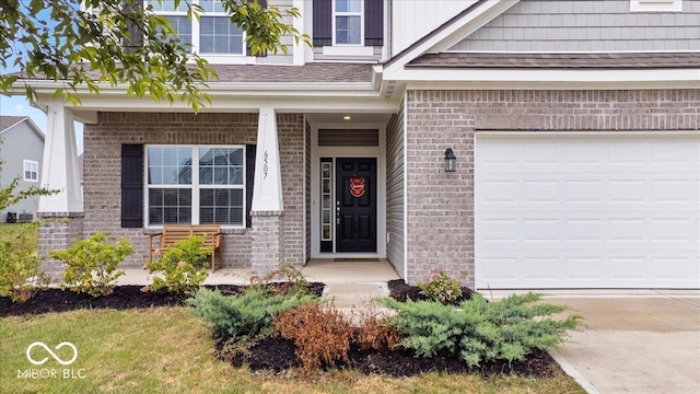 6507 W Whispering Way, Greenfield, IN 46140 - property entrance featuring brick siding, concrete driveway, an attached garage, and a porch