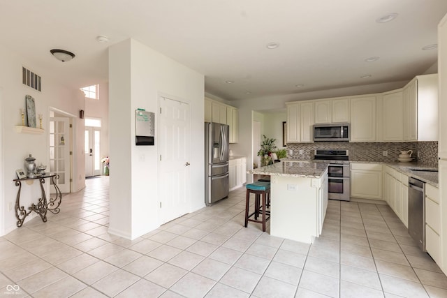 2096 Whitetail Ct, Avon, IN 46123 - kitchen with appliances with stainless steel finishes, backsplash, light tile patterned flooring, a kitchen island, and a breakfast bar
