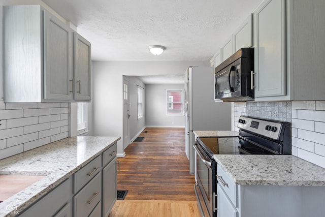 2164 E Raymond St, Indianapolis, IN 46203 - kitchen with black microwave, stainless steel electric range oven, gray cabinets, tasteful backsplash, and dark wood-type flooring