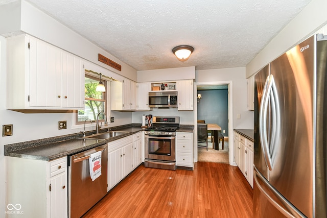 6580 Kings Ct, Avon, IN 46123 - kitchen featuring stainless steel appliances, dark countertops, wood finished floors, white cabinets, and a textured ceiling