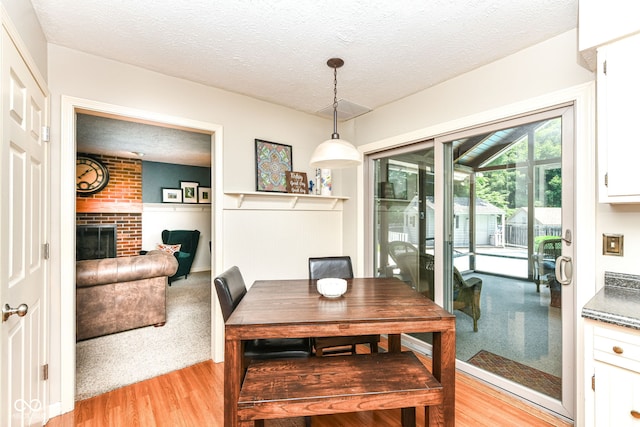 6580 Kings Ct, Avon, IN 46123 - dining room featuring light wood-type flooring, a brick fireplace, and a textured ceiling