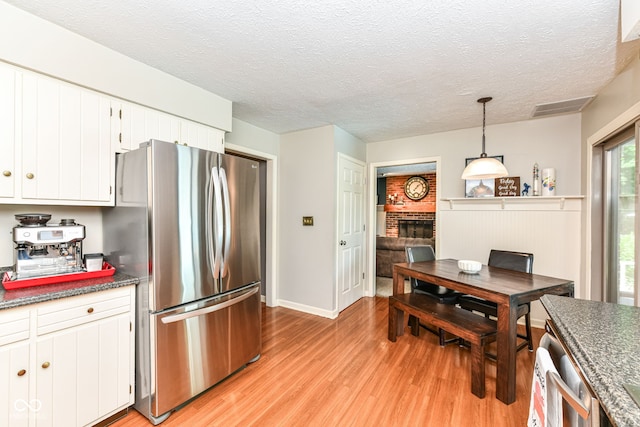 6580 Kings Ct, Avon, IN 46123 - kitchen with freestanding refrigerator, light wood finished floors, a fireplace, white cabinets, and hanging light fixtures