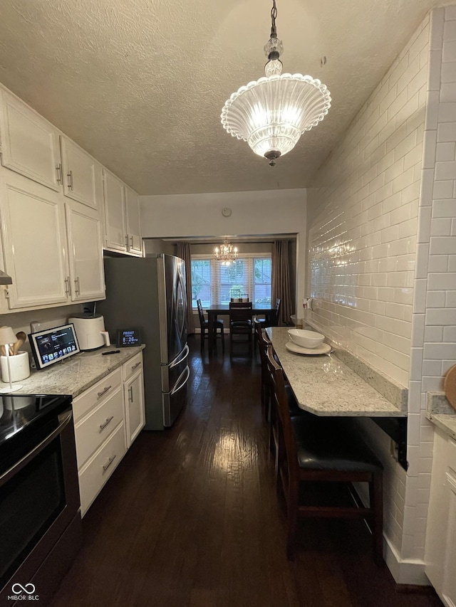 9467 N Michigan Rd, Fairland, IN 46126 - kitchen with a chandelier, appliances with stainless steel finishes, white cabinets, dark wood finished floors, and light stone counters