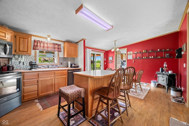2248 W State Road 58, Seymour, IN 47274 - kitchen featuring appliances with stainless steel finishes, a wood stove, tasteful backsplash, light wood-type flooring, and a textured ceiling