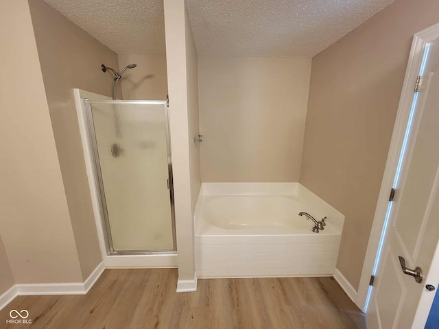 11070 Long Lake Ln, Fishers, IN 46037 - bathroom featuring wood finished floors, a stall shower, a garden tub, and a textured ceiling